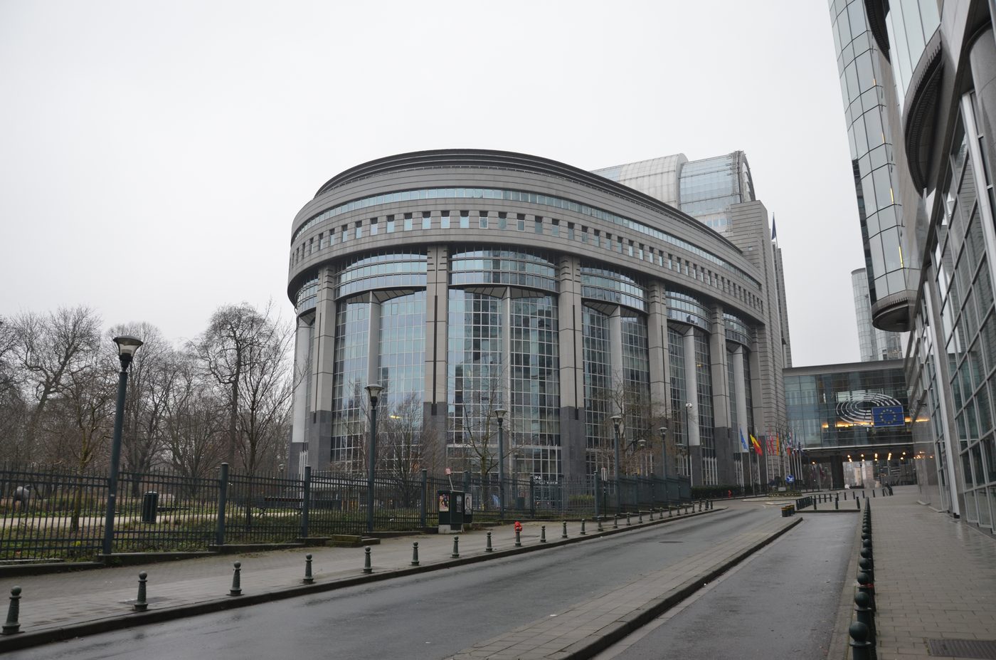 The European Parliament building in Brussels, with EU member state flags flying outside the entrance.