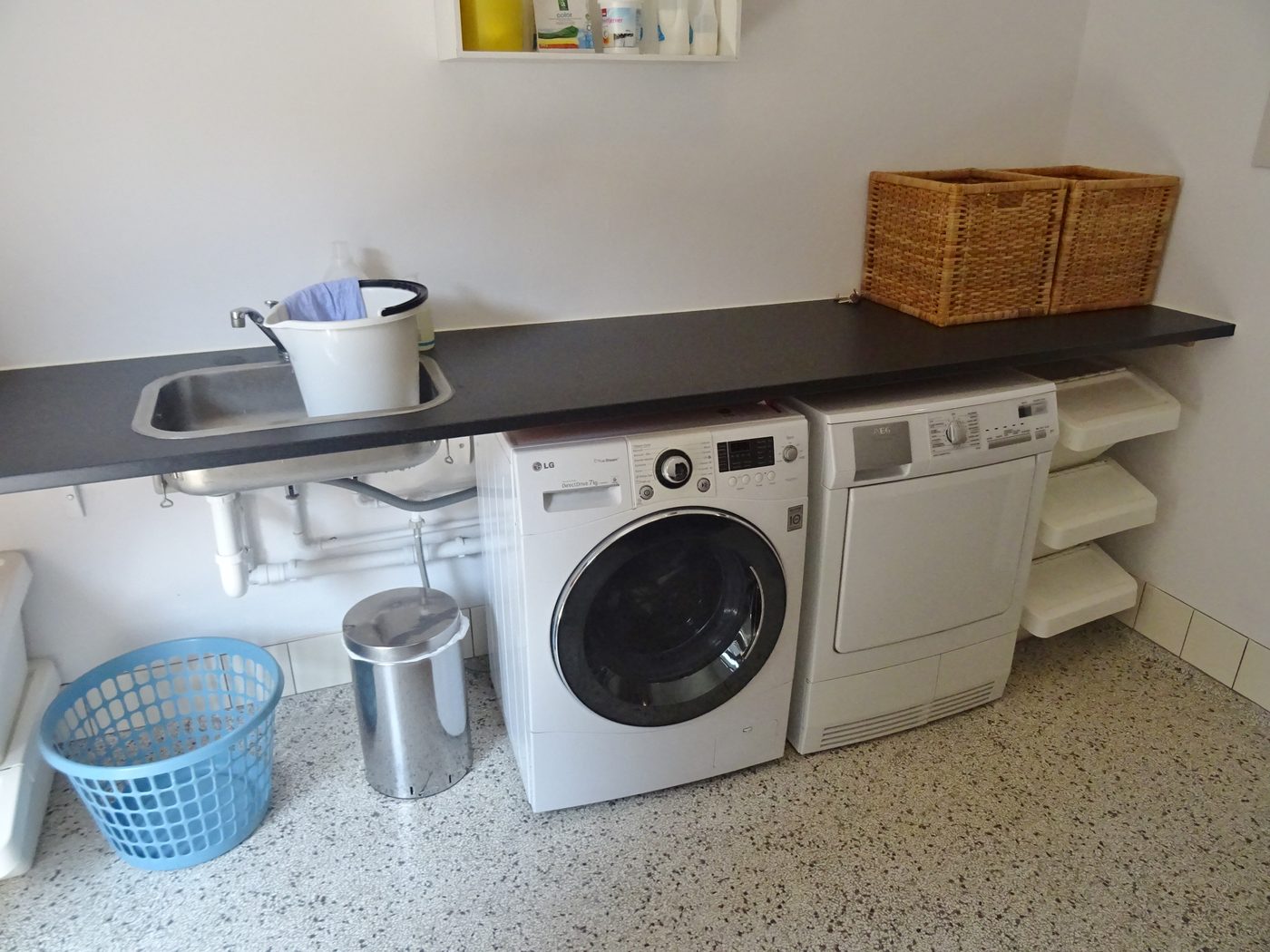 An LG front-loading washing machine and AEG tumble dryer installed side by side under a counter in a European laundry room